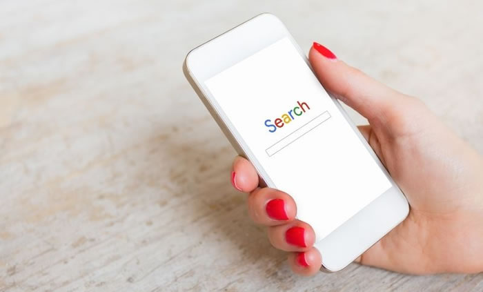 Woman holding mobile phone using Google Search